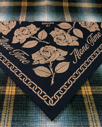 A folded black screen printed bandana with gold rose illustrations, chain links and 'Alone Time' type, laid on a plaid background
