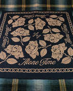 Black screen printed bandana with gold rose illustrations, chain links and 'Alone Time' type, laid on a plaid background