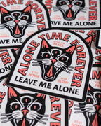 Pile of Die-Cut Sticker designs with a three eyed cat illustration and typography reading 'Alone Time Forever', 'Leave Me Alone', Give Me Peace' and 'Stay Home, Live Slow'.